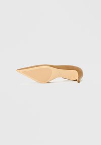 Nøgen højhælet sko med spids tå og slank hæl, med en glat overflade øverst og ribbet ydersål for godt greb.