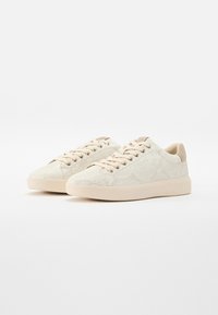 Baskets beige clair avec un motif texturé imitant le cuir de serpent. Elles disposent de lacets crème et d'une semelle en caoutchouc simple.