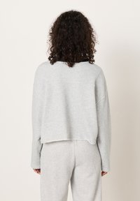 Hall, lühendatud dressipluus pehmest materjalist, pikkade varrukatega ja ümara kaelusega, millel on toorikäänisega ääris ja lõdva lõikega.