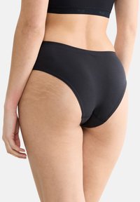 Zwarte katoenen hipsteronderbroek met een gladde textuur en een brede tailleband. Beschikt over strakke lijnen en minimale stitching.