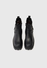 Crne gležnjače od teksturirane kože, s okruglim vrhom, bočnim cipzom i čvrstim potplatima s profilom. Podstavljene su leopard uzorkom.