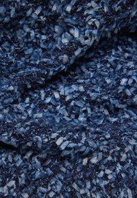 Blauer strukturierter Stoff in verschiedenen Schattierungen, mit einem plüschigen Gefühl und subtilen metallischen Fasern, die ein geschichtetes und komplexes Muster erzeugen.