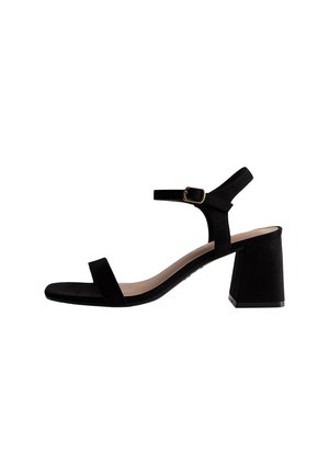 Sandale en daim noire avec un talon bloc, une bride ajustable à la cheville, un bout ouvert et un design minimaliste avec une seule bride à l'avant.