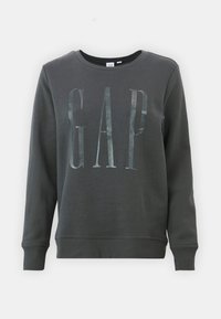 Felpa grigia scura realizzata in materiale morbido, con un grande logo riflettente "GAP" sul davanti. Girocollo e maniche lunghe.