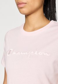 Ροζ βαμβακερό t-shirt με ανάγλυφο, κεντημένο λογότυπο «Champion» στο στήθος και κλασικό στρογγυλό λαιμόκοψη.