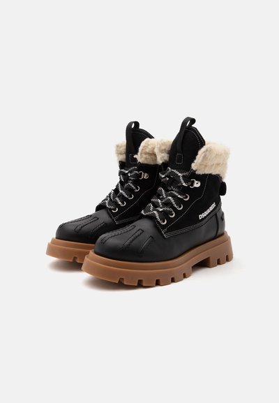Bottes d'hiver noires à lacets avec semelles épaisses marron, doublure polaire beige et logo DSQUARED2 blanc sur le côté.