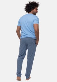 T-shirt bleu clair à manches courtes associé à un pantalon de pyjama bleu à motifs avec un design géométrique. Coupe décontractée et texture douce.