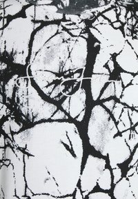 T-shirt graphique noir et blanc avec un motif craquelé, en coton doux, col rond, et "Sean John" brodé en blanc.