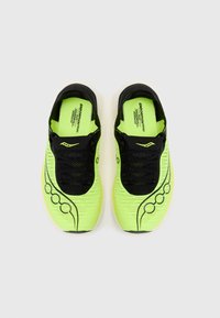 Zapatillas de correr amarillas neón con parte superior de malla negra, tejido texturizado y un diseño curvo que cuenta con una suela de goma blanca y acentos laterales.