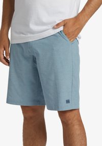 Light blue shorts made of soft fabric with a woven texture. Features side pockets and a small navy logo detail on the leg.