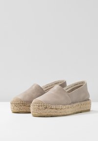 Espadrillas beige con tomaia in pelle liscia, design arrotondato e suola in juta intrecciata con una finitura textured.