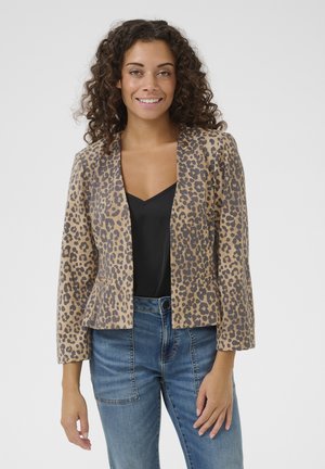 Leoprint-Jacke in Braun und Schwarz, taillierte Passform mit einem Peplum-Saum, aus einem glatten Stoff gefertigt. Getragen über einem schwarzen Oberteil und Jeans.