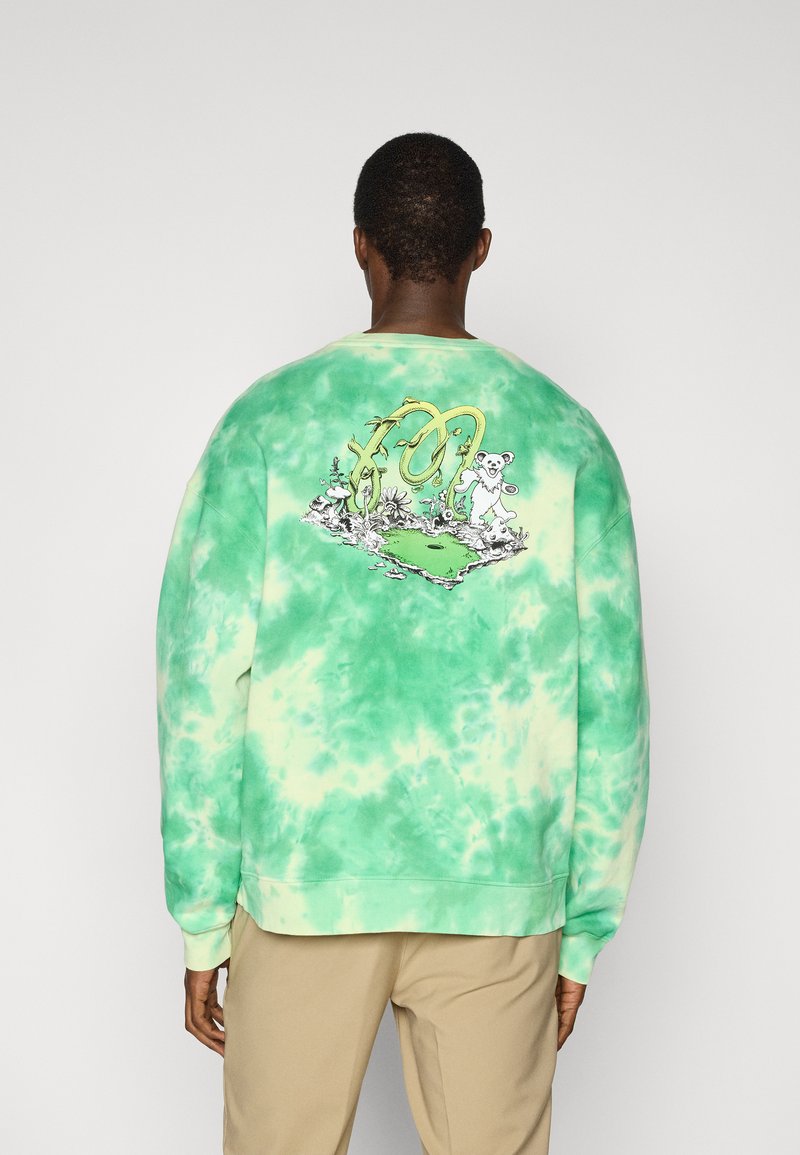 Πράσινο φούτερ με τεχνική tie-dye που διαθέτει ένα γραφικό σχέδιο στην πλάτη με καρτουνίστικα στοιχεία. Τελειώματα με ριμπ μανσέτες και στρίφωμα για άνετη εφαρμογή.