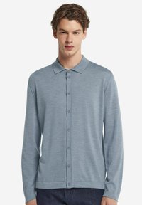 Jasnoniebieska, długosleeve polo z kołnierzykiem, zapięciem na guziki z przodu oraz miękką, teksturowaną tkaniną. Udekorowana równomiernie rozmieszczonymi guzikami.