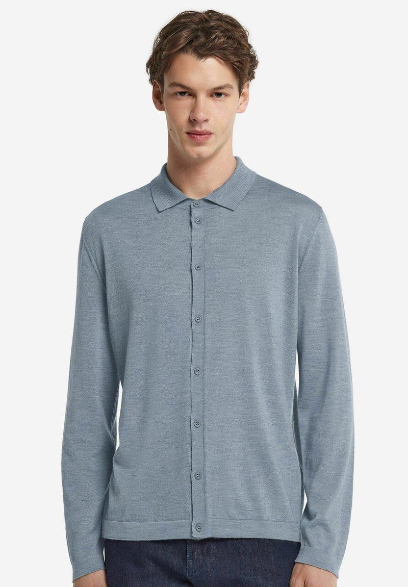 Jasnoniebieska, długosleeve polo z kołnierzykiem, zapięciem na guziki z przodu oraz miękką, teksturowaną tkaniną. Udekorowana równomiernie rozmieszczonymi guzikami.