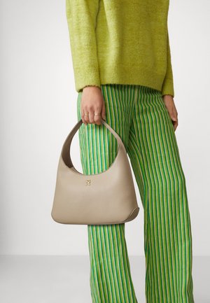 Beige läderhandväska med ett böjt handtag, med en subtil präglad logotyp. Matchad med gröna och vita randiga byxor och en strukturerad limefärgad tröja.