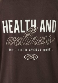 Tissu brun foncé avec texte blanc et gris indiquant : « SANTÉ ET bien-être, NYC - FIFTH AVENUE 00981. 1998 » en polices variées.