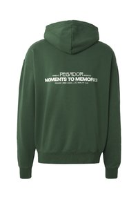 Sweat à capuche vert avec texte blanc au dos indiquant « PEGADOR MOMENTS TO MEMORIES » et texte de marque supplémentaire plus petit.