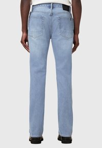 Jeans di denim azzurro con taglio dritto, dotati di due tasche posteriori e una finitura tessurizzata. Etichetta nera in vita visibile.