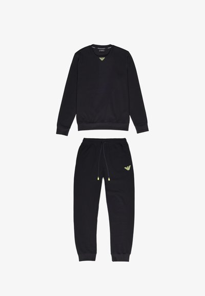 Felpa nera e joggers coordinati in tessuto morbido. Presenta accenti gialli del logo sul petto e sulla coscia, polsini elasticizzati e coulisse regolabile.