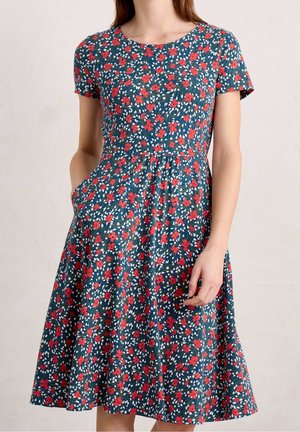 Bloem jurk met korte mouwen, met een marineblauwe achtergrond, rode en witte bloemen, A-lijn vorm en zijzakken. Gemaakt van lichtgewicht stof.