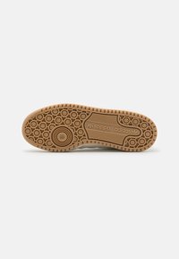 Gumová podrážka s kruhovým vzorem, se znakem adidas. Hladký povrch s kontrastními světlými a tmavými barevnými sekcemi.