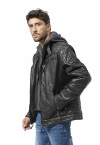 Lederjacke mit gesteppter Schulterverzierung, schwarze Farbe, Reißverschlusstaschen und einem grauen Kapuzenfutter, kombiniert mit blauen Jeans.