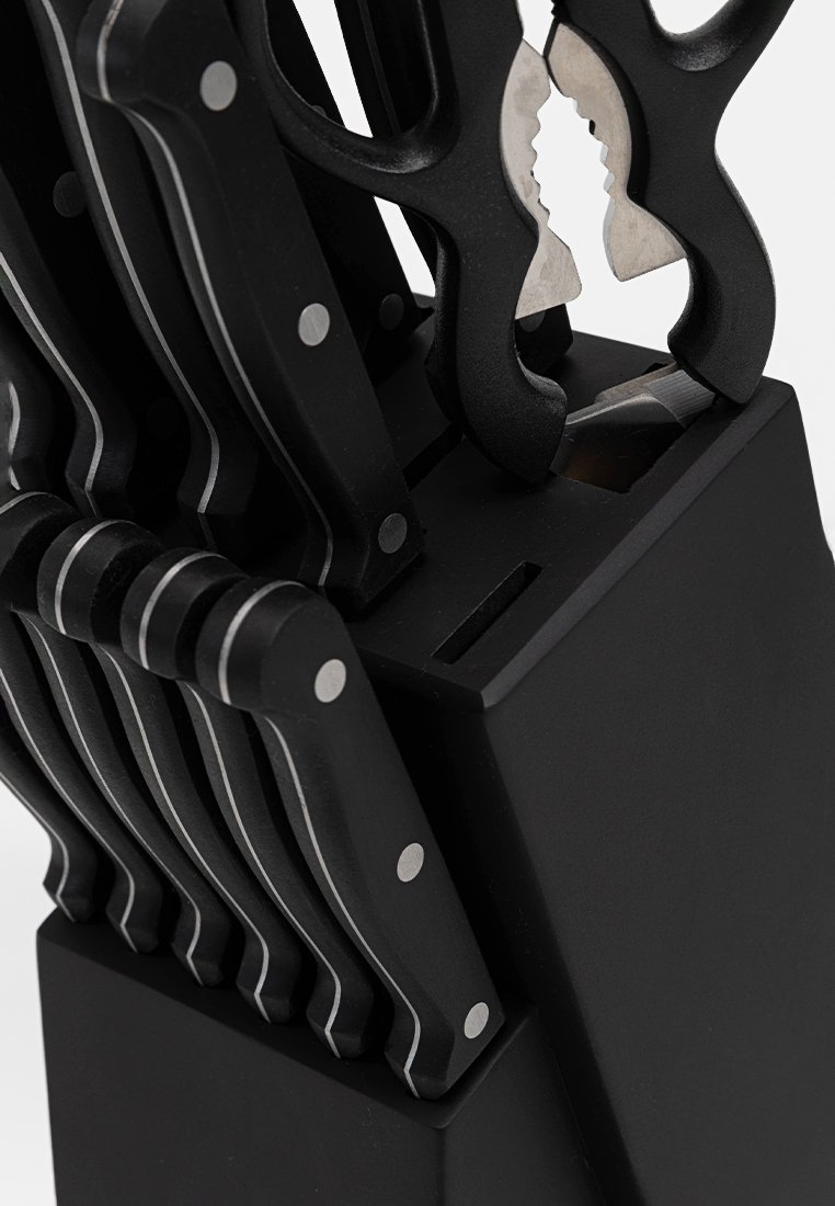 Czarny blok na noże zawierający wiele noży z czarnymi uchwytami i srebrnymi akcentami, charakteryzujący się unikalnym kształtem i otwartą przestrzenią na narzędzia.