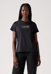 T-shirt in cotone nero a maniche corte con scollatura a girocollo. Presenta un logo Levi's ricamato a contrasto sul davanti.