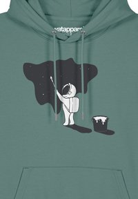 Tarnfarbene Kapuzenjacke mit einem grafischen Motiv eines Astronauten, der eine schwarze Weltraumszene malt, mit einem Farbkübel daneben. Mit Kordelzügen und Fronttasche.