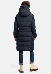 Manteau en duvet bleu marine avec capuche, doté de panneaux matelassés, d'un cordon de serrage ajustable et d'un accent logo à l'ourlet. Manches longues et longueur mi-cuisse.