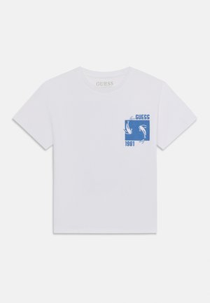 T-shirt blanc à manches courtes avec un graphique bleu de deux poissons dans un carré, le texte "GUESS" au-dessus et "1981" en dessous du motif sur la poitrine.