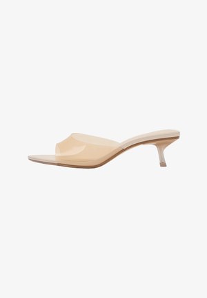 Beige offene Mule-Sandale mit transparentem oberen Riemen und niedrigem, spitz zulaufendem Kittenabsatz auf weißem Hintergrund.