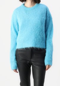 Pull en maille bleu clair, moelleux, à manches longues et col rond, avec un design court et une coupe ample.