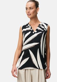 Top senza maniche di colore nero con un motivo a foglie bianco e marrone, design a V, tessuto morbido e vestibilità rilassata, con dettagli di pieghe sottili.