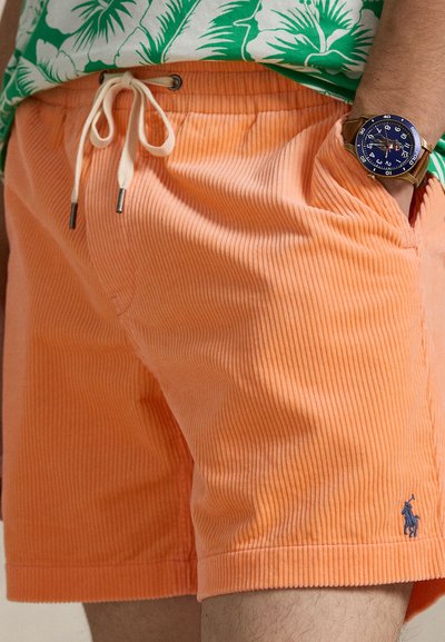 Πορτοκαλί σορτς από κορντόρι με ελαστική μέση και κορδόνι, διαθέσιμα πλαϊνές τσέπες και μικρό μπλε λογότυπο κοντά στο τελείωμα. Μαλακή υφή και ριμπ υφή.