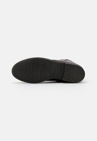Semelle en caoutchouc noir avec un motif de grip texturé, présentant un supérieur lisse de couleur foncée et des détails subtils. Design léger et élégant.