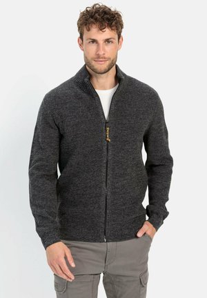Grauer Reißverschluss-Pullover mit strukturierter Strickmuster, geripptem Kragen und zwei vorderen Taschen, kombiniert mit einem weißen Innenhemd und beigen Hosen.