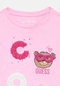 Hele roosa puuvillane t-särk, millel on sädelev "C", litritega kaunistatud muster ja prillidega multikategelane. Masinpestav.