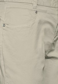 Ljust beige bomullsshorts med en slät yta, featuring en bakficka och silverknappdetalj. Enkel design utan utsmyckningar.