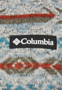 Pull en tricot avec un mélange de gris, bleu et tons terre ; orné de formes géométriques et d'une étiquette noire Columbia.
