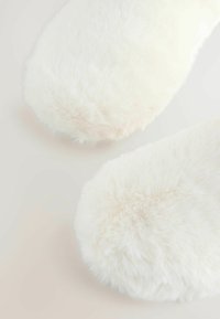 Pehmead valged sünteetilisest karvast susside varbad, näidatud heledal taustal, rõhutades luksuslikku tekstuuri ja ümarat kuju.