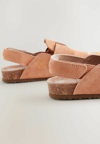 Rosa mockaskinn slingback-sandaler med en texturerad korksula och blommönster på innersulan, med en böjd, öppen häl-design.