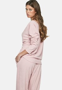 Lichtroze loungewear set bestaande uit een relaxed-fit lange mouw top en bijpassende broek met een zachte textuur en zijzakken.