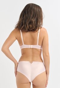 Ein hellrosa Lingerie-Set, das einen glatten Satin-BH mit verstellbaren Trägern und passenden hochgeschnittenen Slips umfasst, akzentuiert mit einem dekorativen Rückendetail.