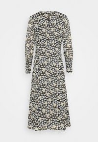 Sort og hvid blomstret langærmet midikjole med tætsiddende talje og knaplukning med nøglehul bagi på ensfarvet baggrund.