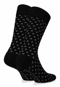 Czarne skarpetki wzorzyste w diamentowy wzór, wykonane z miękkiego materiału, z prążkowanym ściągaczem oraz wzmocnioną piętą i palcami.