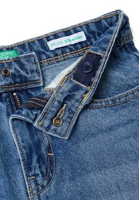 Vaqueros de mezclilla azul con corte recto, que cuentan con cierre de botón metálico, bragueta con cremallera y costuras contrastantes. La etiqueta dice "BRUCE-STRAIGHT."