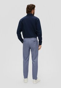 Marineblauwe overhemd, blauwe en witte geblokte broek met twee achterzakken en witte sneakers. Klassieke, op maat gemaakte pasvorm.