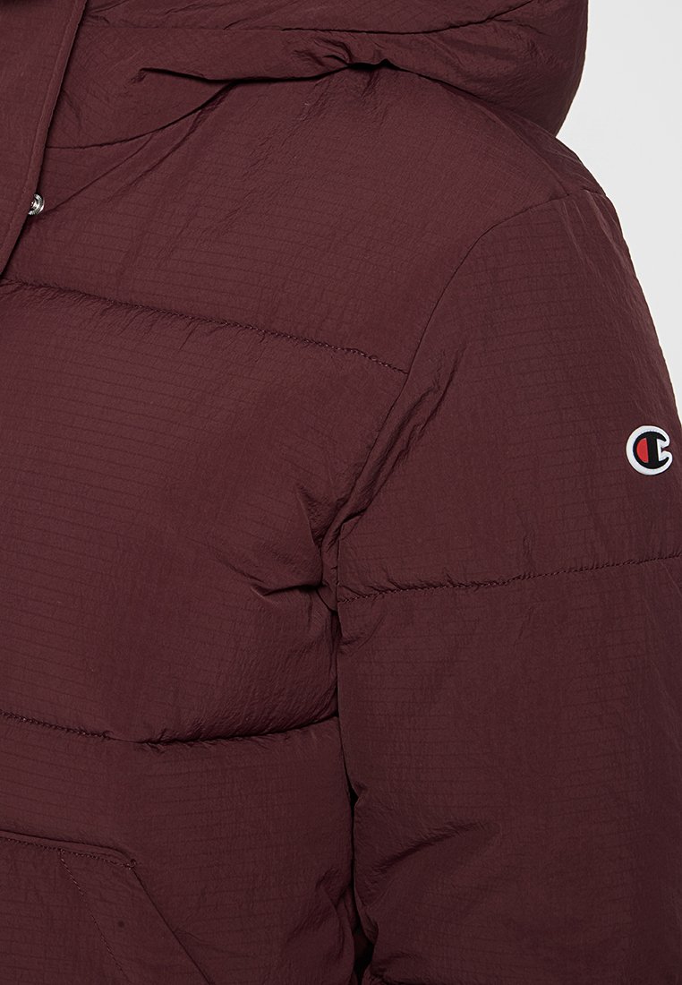 Giacca a vento bordeaux con superficie texturizzata, dotata di cappuccio, motivo trapuntato e un piccolo logo sul manica sinistra.